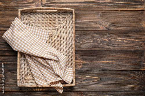 Wicker tray with napkin on wooden background