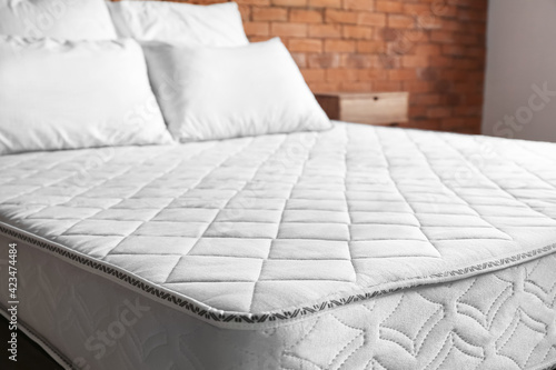 Bed with comfortable orthopedic mattress in room photo