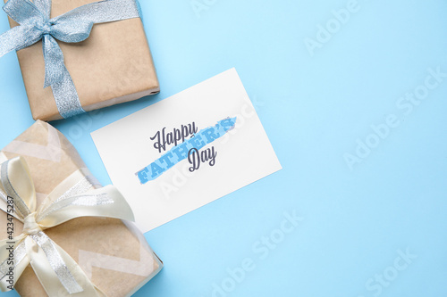 Gift boxes and greeting card for Father's Day celebration on color background