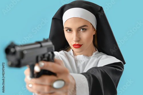 Young nun with gun on color background photo