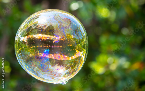 A large soap bubble flies in the park.