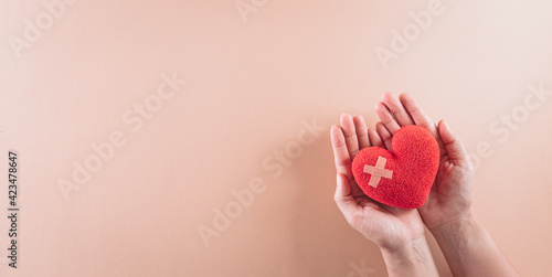 Top view of hand holding red heart on pastel background. World health day and medical concept.