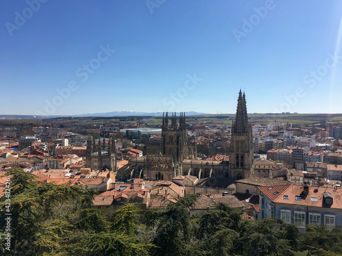 Panoramic view of Burgos with its famous cathedral surrounded by buildings in the foreground and agricultural fields and mountains in the background, on the horizon.