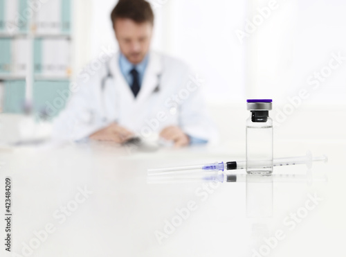 doctor in office with vaccine syringe and ampoule isolated on the desk  coronavirus  covid 19 vaccination