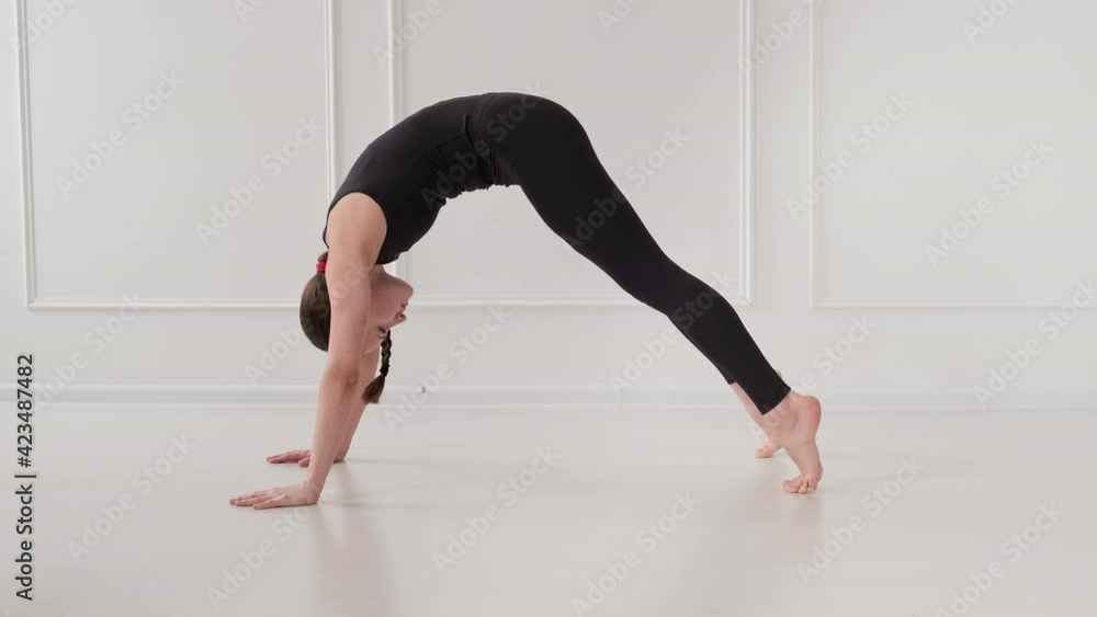 Brunette woman stretching at light background. Young female doing yoga exercises. Healthy lifestyle. Woman practicing yoga. Body care. 4K, UHD Brunette woman stretching at light background. Young female doing yoga exercises. Healthy lifestyle. Woman practicing yoga. Body care. 4K, UHD