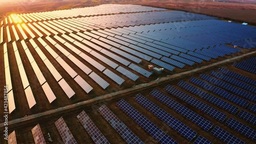 Aerial view of Solar Panels Stand At Sunrise. Flyover Fields Green Energy Landscape. Concept of Electrical Power, Ecology, Innovation, Global Warming. Nature environment. 