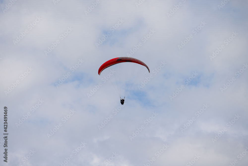 A Paraglider flying into the sky with clouds on a sunny day. A Paraglider flying into the sky with clouds on a sunny day.