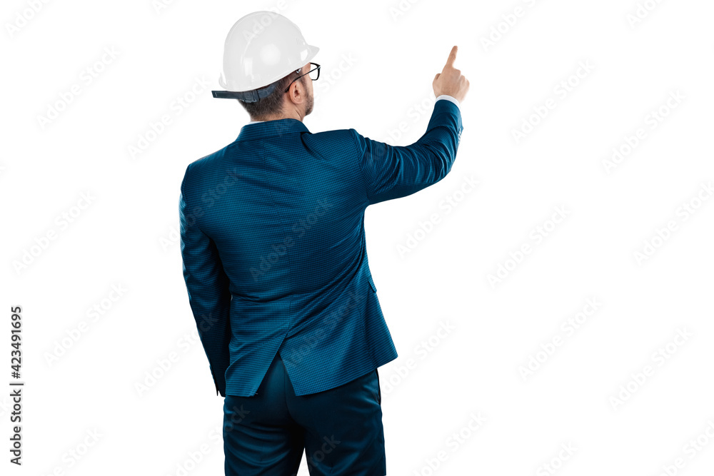 A man in a business suit, an architect with a white helmet on his head points his finger at something, isolated on a white background. Architecture, construction concept. A man in a business suit, an architect with a white helmet on his head points his finger at something, isolated on a white background. Architecture, construction concept.