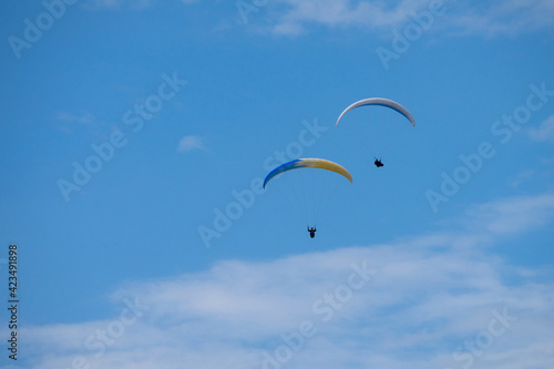 Two para gliders flying on a cloudy day.