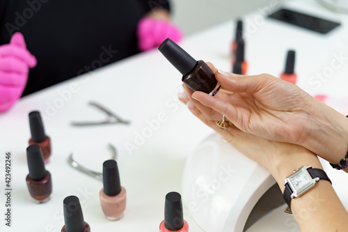 Close up details of woman hands making manicure and chosing nail polish in luxury beauty salon with modern equipment  colors  nail service  perfect client hands.