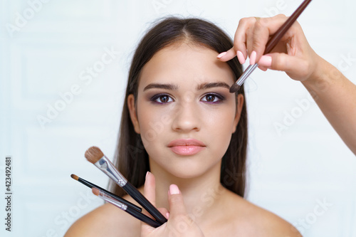 Professional makeup artist working with client in dressing room on white background