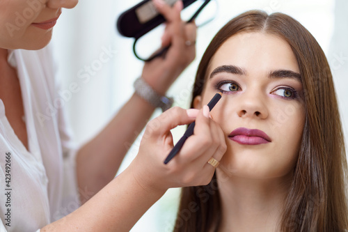 Professional makeup artist working with client in dressing room