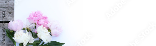 Photo of white, pink pion flowers on wooden background with copy space. Summer concept. Floral background for web site, greeting card, banner, flower shop. Focus on flowers © Elena