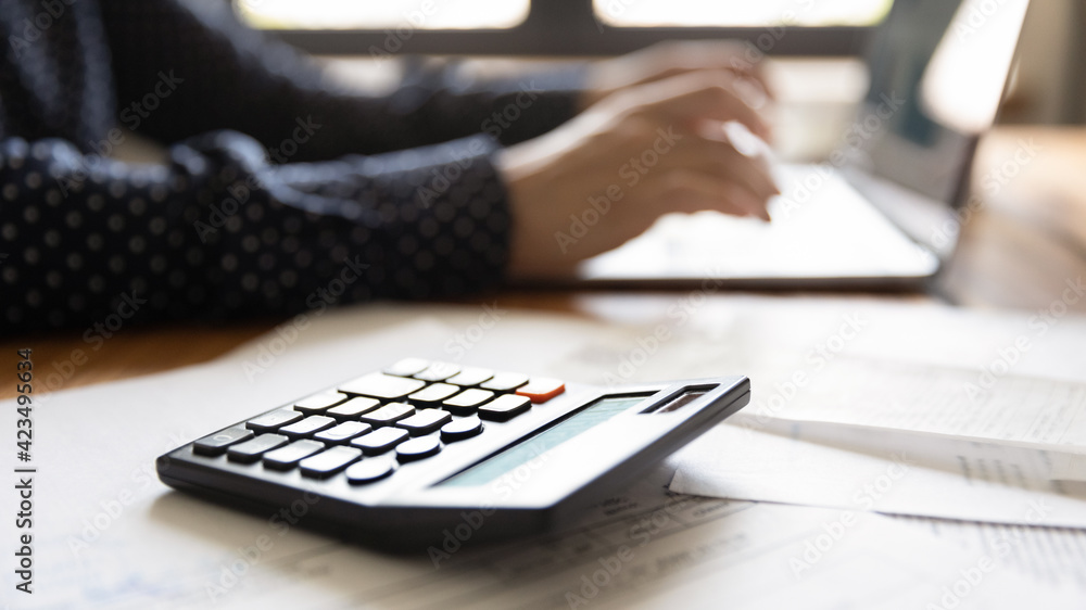 Close up woman using laptop and calculator, calculating bills, checking financial documents, young female managing planning budget, accounting expenses, browsing internet banking service, payment Close up woman using laptop and calculator, calculating bills, checking financial documents, young female managing planning budget, accounting expenses, browsing internet banking service, payment