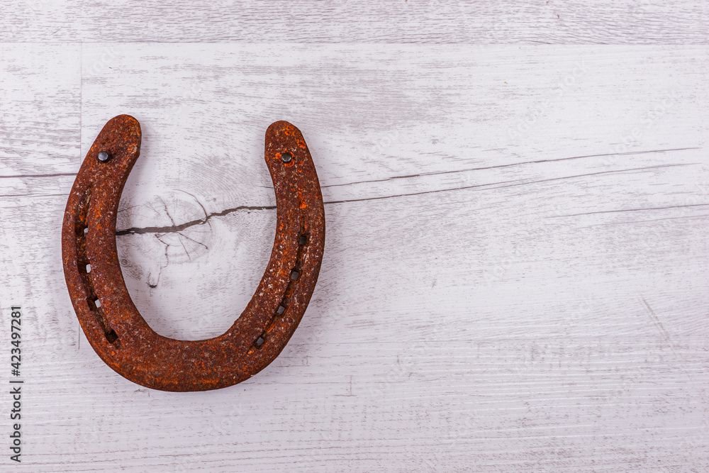 Rusty horseshoe isolated on bright wooden background. Good luck symbol. Top view Rusty horseshoe isolated on bright wooden background. Good luck symbol. Top view