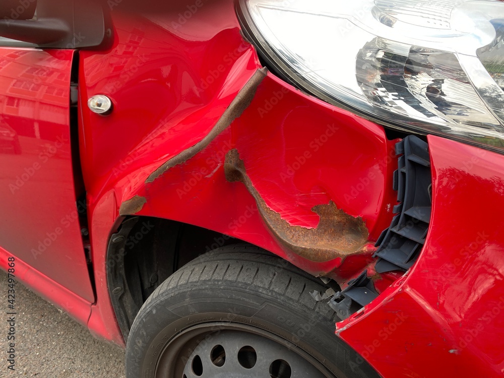 Visible dent on the side of a red car due to an accident