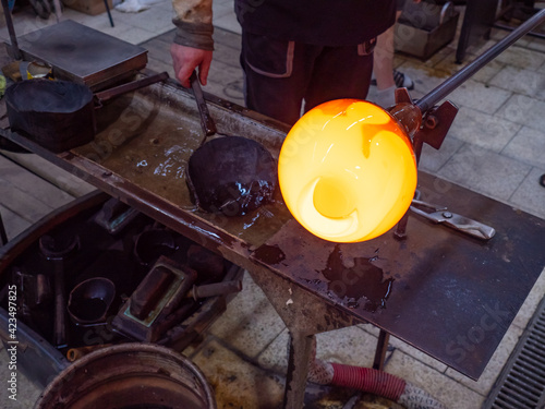 Man Hands Shaping hot glass art piece with wooden tool