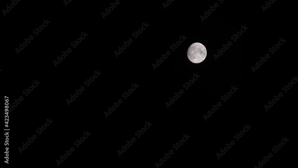 Full moon situated at top right, slowly disappearing in the clouds, at black night sky Full moon situated at top right, slowly disappearing in the clouds, at black night sky