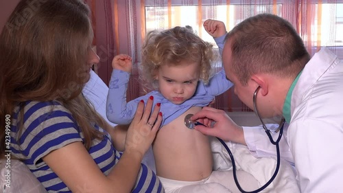 sick girl on her mother knees and doctor male listen her with a stethoscope. 4K