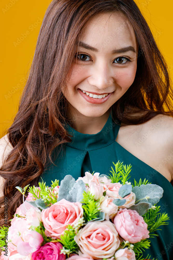 Close up face shot of cute and pretty curly hair Asian female brunette holding flower bouquet with cheerful and happy, studio shot isolated on bright yellow background. Close up face shot of cute and pretty curly hair Asian female brunette holding flower bouquet with cheerful and happy, studio shot isolated on bright yellow background.