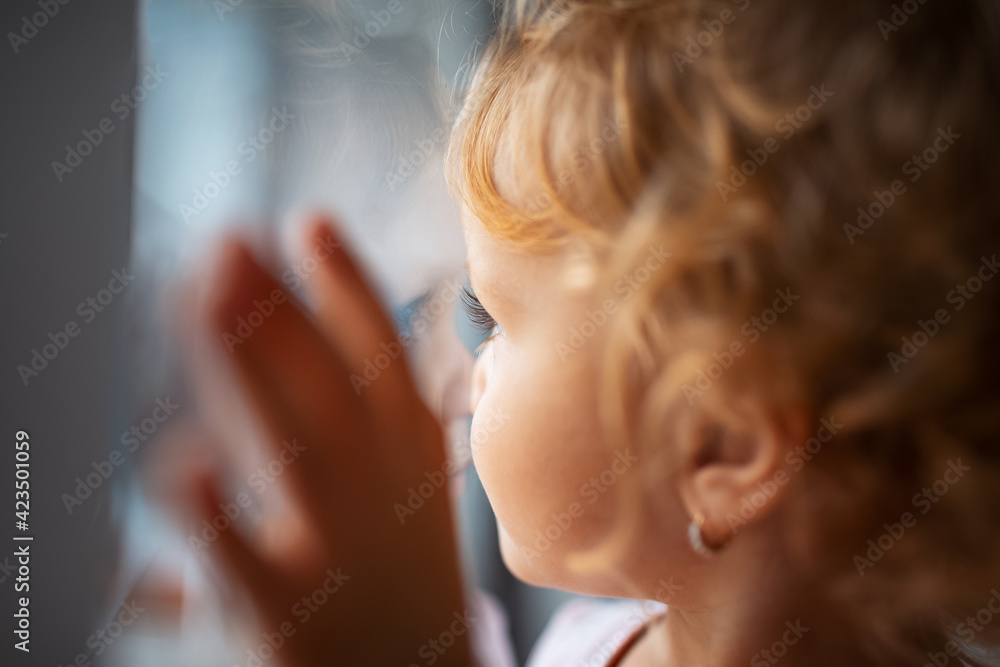 Fototapeta premium Close-up portrait of children girl looking through window.