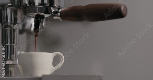 Slow motion man making espresso with single spout portafilter on coffee machine