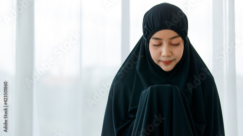 Asian Muslim woman wear black hijab. Show humility to God In faith in Allah is a request for a blessing in a white bedroom. According to the beliefs in Islam. Concept faith Muslim prayer..