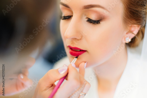 beautiful bride in a white robe with a hairstyle and bright lips. getting ready for the wedding in the morning.
