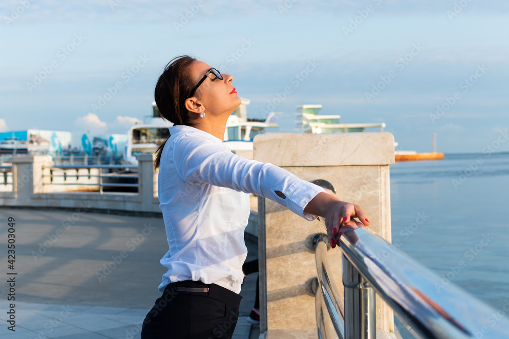 happy businesswoman stands on the pier by the sea