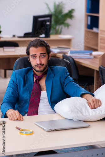 Young male employee coming to work straight from bed