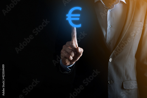 Wallpaper Mural Businessman holds money coin icons EUR or Euro on dark tone background..Growing money concept for business investment and finance Torontodigital.ca