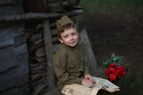 A boy soldier in military uniform with a newspaper Pravda sits on a bench