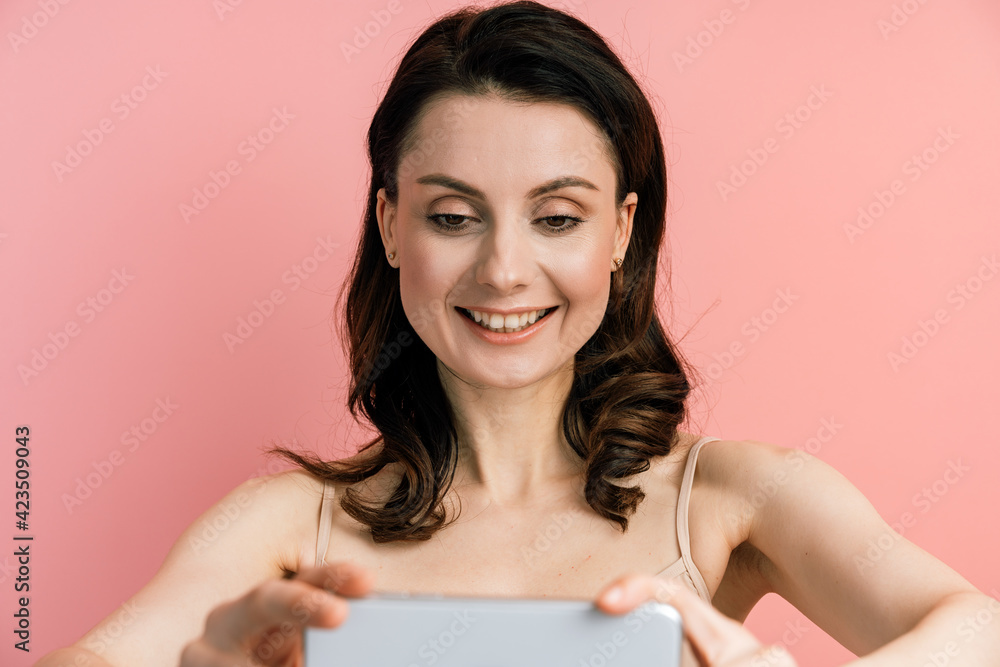 Photo of cute, positive, young woman posing isolated over pink wall background, make selfie with camera. Girl taking selfie on phone. Photo of cute, positive, young woman posing isolated over pink wall background, make selfie with camera. Girl taking selfie on phone.