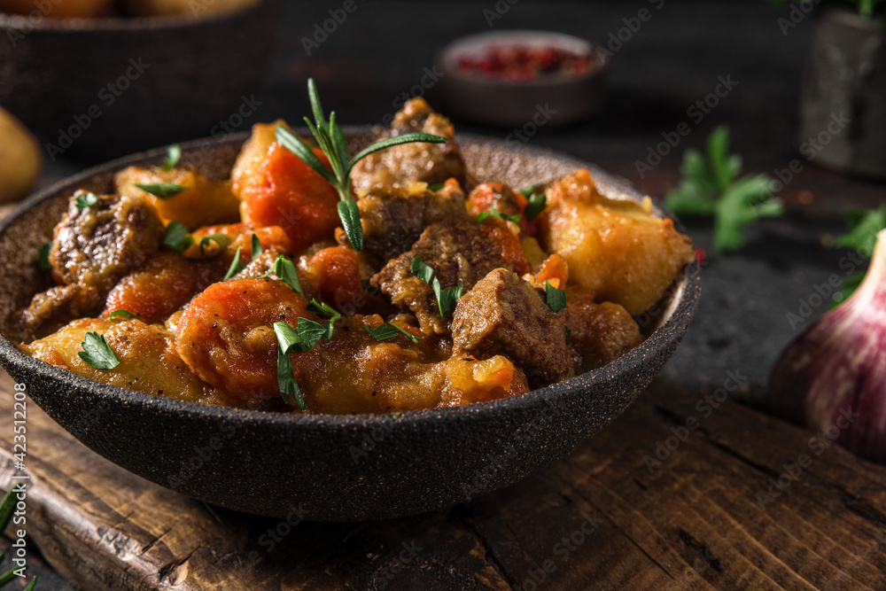 Irish stew made with beef meat, potatoes, carrots and herbs in a plate on black background. close up