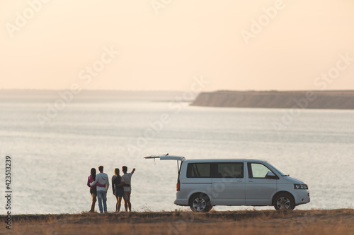 Photography The four friends standing near the minivan against the sunset sky