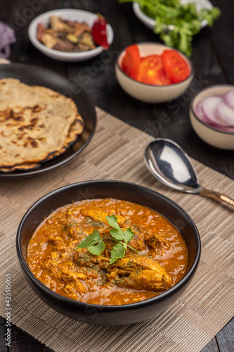 spicy gravy chicken served in a black bowl with chapati