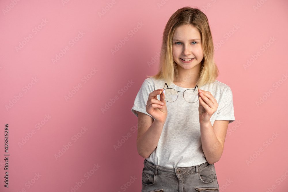 Charming, pretty girl with glasses in her hands posing on the background of an empty wall. Girl standing on a pink background in the studio Charming, pretty girl with glasses in her hands posing on the background of an empty wall. Girl standing on a pink background in the studio