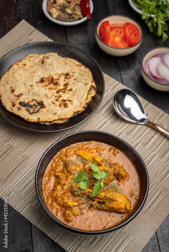 spicy gravy chicken served in a black bowl with chapati