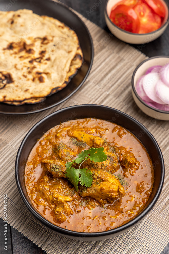 spicy gravy chicken served in a black bowl with chapati spicy gravy chicken served in a black bowl with chapati