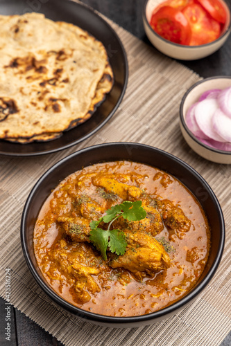 spicy gravy chicken served in a black bowl with chapati © PrabhjitSingh