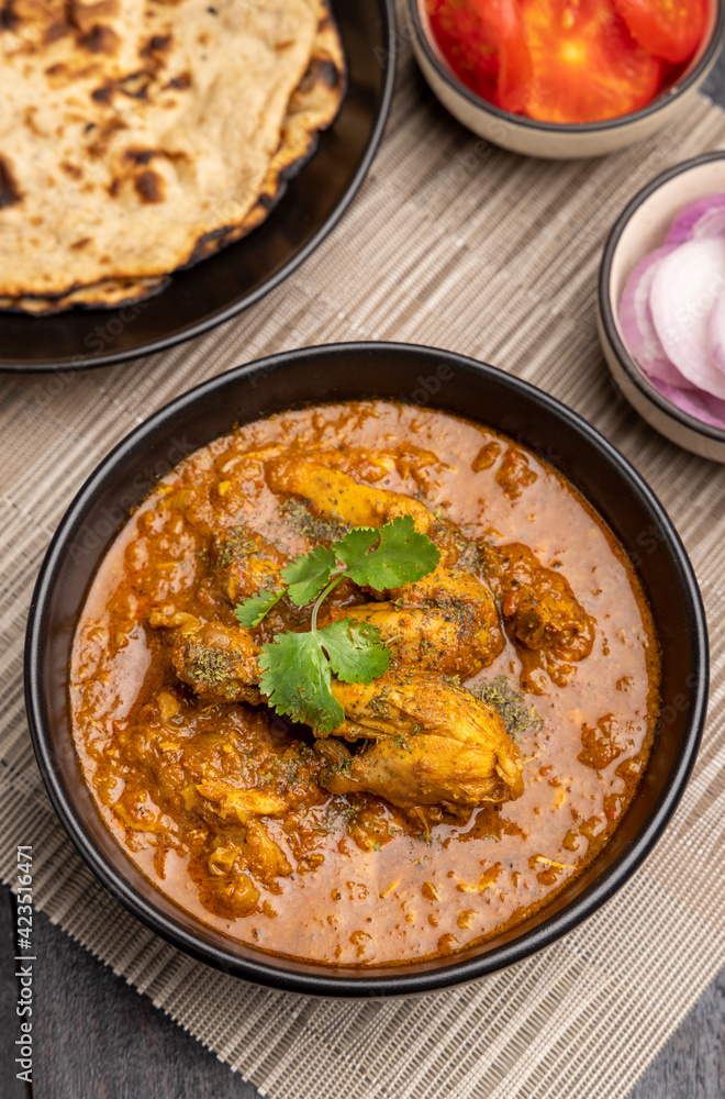 spicy gravy chicken served in a black bowl with chapati spicy gravy chicken served in a black bowl with chapati
