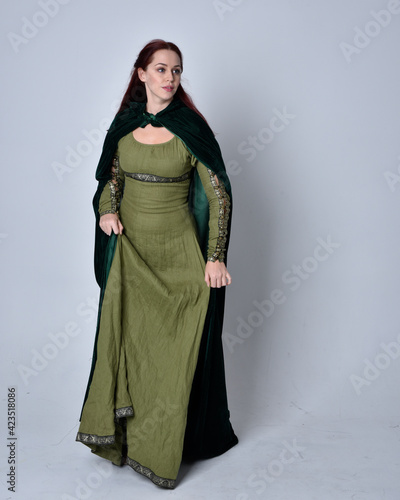Fotografie full length portrait of red haired girl wearing celtic, green medieval gown with fantasy velvet cloak