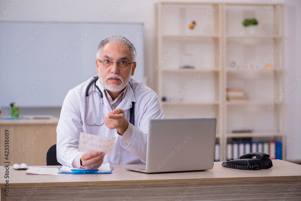 Old male doctor cardiologist working in the clinic Old male doctor cardiologist working in the clinic