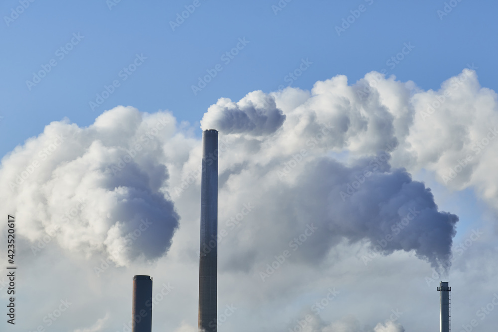 Close-up view of CHP plant pipes with smoke in the sunny day.