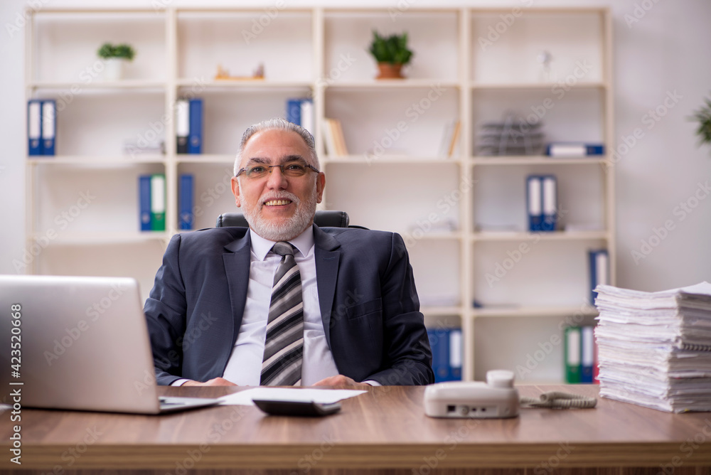 Aged male employee unhappy with excessive work in the office Aged male employee unhappy with excessive work in the office