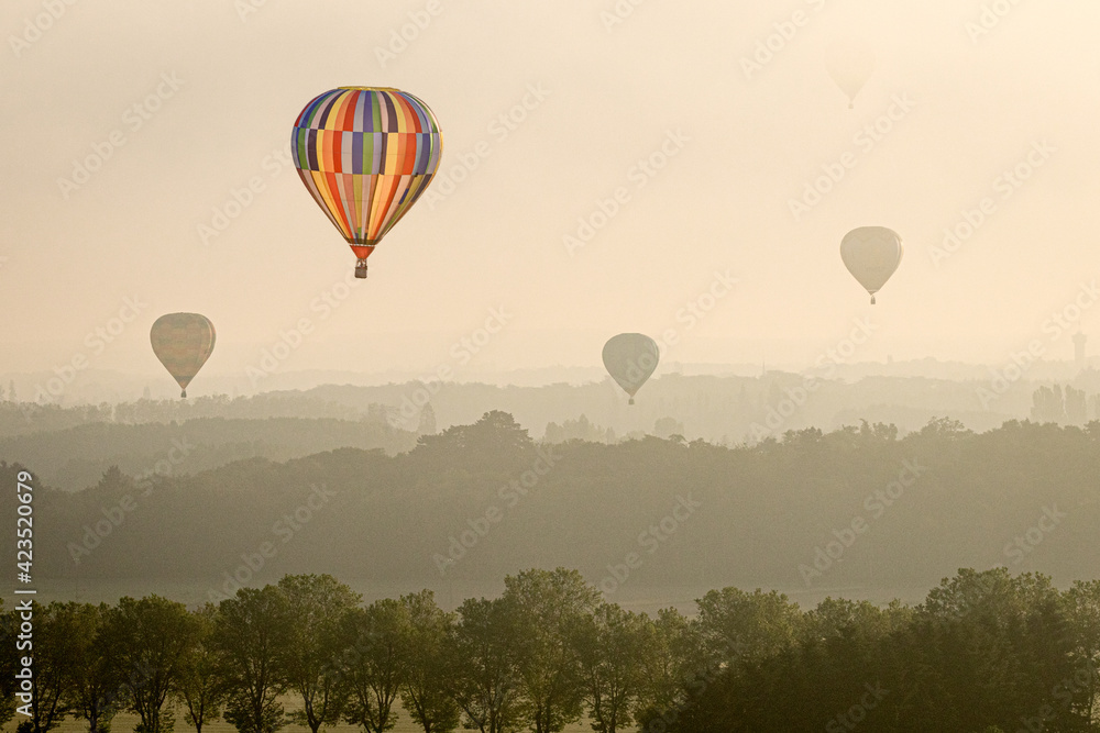 Obraz premium vier Ballons fliegen über die poetische Silhouette der Landschaft in der goldenen, stark dunstigen Morgendämmerung