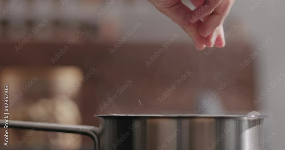 Slow motion man hand salting bopiling water for pasta in saucepan closeup Slow motion man hand salting bopiling water for pasta in saucepan closeup