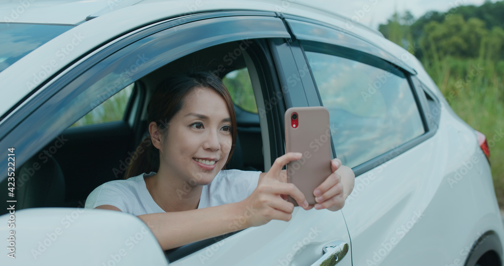 Travel woman use cellphone to take photo and sit inside car