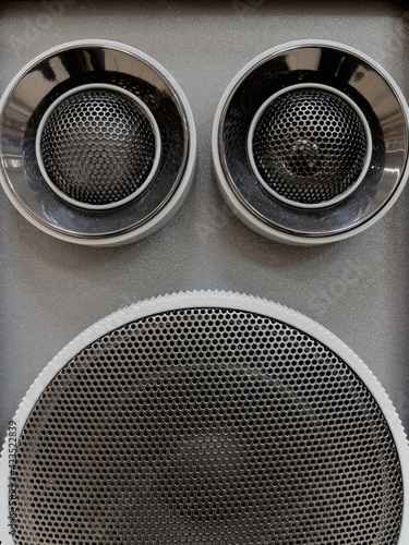 Close-up of musical stereo speaker with protective grill. Modern grey and black audio speaker or music column for background.
