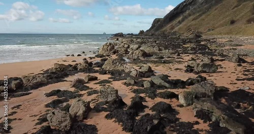 4k aerial footage over water and rocks at Elie Chain Walk, a famous via ferrata walk over rocky cliffs in East Neuk of Fife, Scotland.